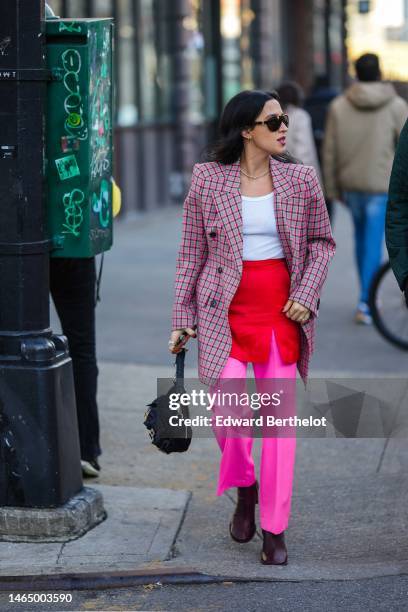 Guest wears black futurist sunglasses, gold earrings, a rhinestones necklace, a white ribbed tank-top, a gray with red and neon pink checkered print...