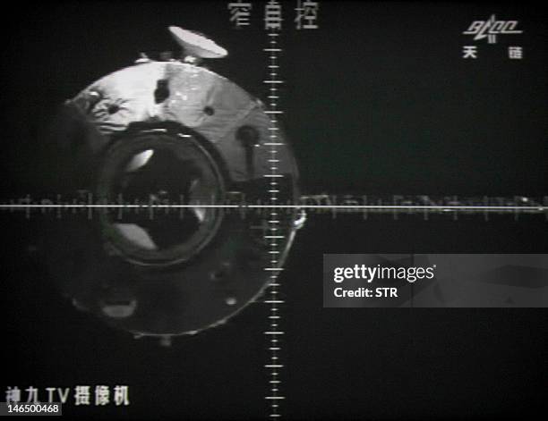 Photo of the giant screen at the Jiuquan space center shows the Tiangong-1 module is seen via a camera in the Shenzhou-9 spacecraft before the...