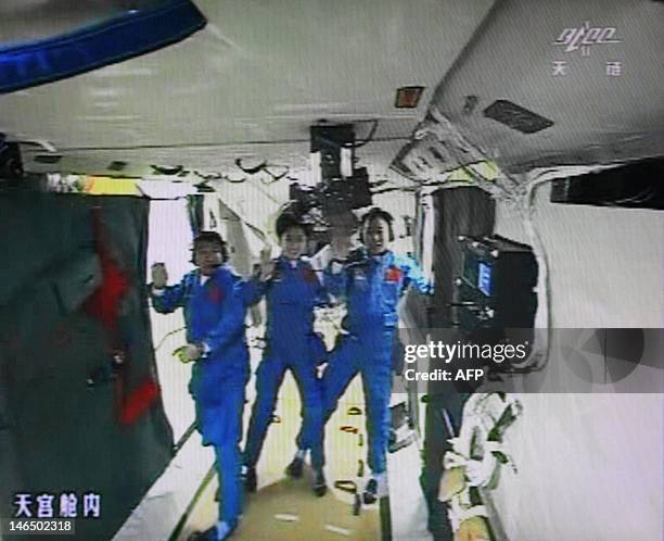 Photo of the giant screen at the Jiuquan space center shows three Chinese astronauts Liu Wang, Jing Haipeng and Liu Yang in the Tiangong-1 module on...