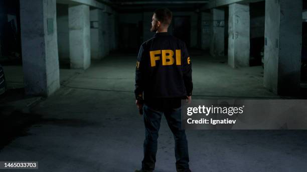 fbi agent standing in a dark wharehouse. fbi background with a copy space - fbi warning stock pictures, royalty-free photos & images