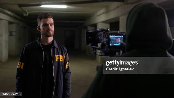 an operator shooting a scene with an fbi agent in a dark underground parking garage - mafia movies stockfoto's en -beelden