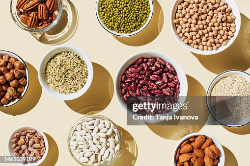 Various kinds of vegan protein sources on beige background. Set of food supplements. Gluten free cereals as ground hemp seeds, quinoa. Nuts and legumes (green mung beans, chick-pea, red lentil, kidney bean, almonds, hazelnuts). Flat lay, top view Various kinds of vegan protein sources on beige background. Set of food supplements. Gluten free cereals as ground hemp seeds, quinoa. Nuts and legumes (green mung beans, chick-pea, red lentil, kidney bean, almonds, hazelnuts). Flat lay, top view