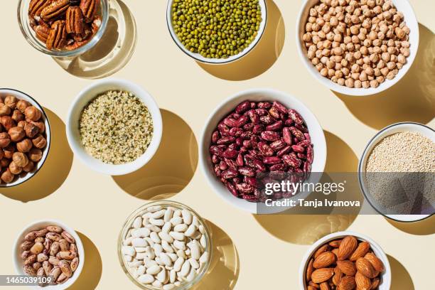 various kinds of vegan protein sources on beige background. set of food supplements. gluten free cereals as ground hemp seeds, quinoa. nuts and legumes (green mung beans, chick-pea, red lentil, kidney bean, almonds, hazelnuts). flat lay, top view - quinoa and chickpeas stock pictures, royalty-free photos & images