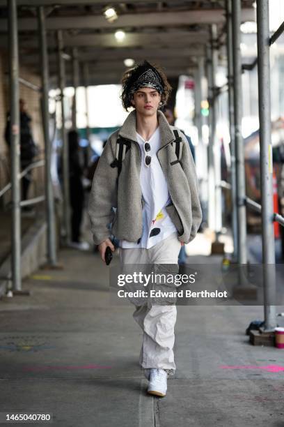 Guest wears a black and white print pattern scarf as a headband, a white shirt, white sunglasses, a pale gray fluffy zipper oversized sweater, white...