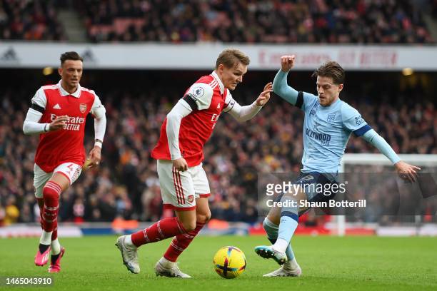 Martin Odegaard of Arsenal is challenged by Mathias Jensen of Brentford during the Premier League match between Arsenal FC and Brentford FC at...