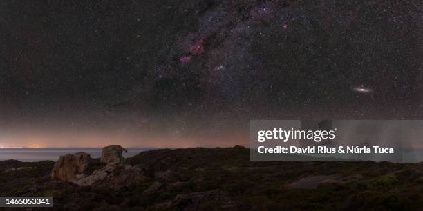 milky way and andromeda over a rocky mediterranean landscape - andromeda galaxy stock pictures, royalty-free photos & images