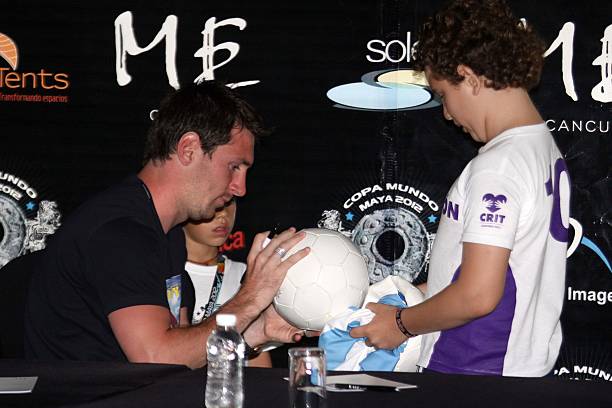 Argentine soccer player Lionel Messi signs a ball during a press conference before a benefit match for disabled children on June 16, 2012 in Cancun,...