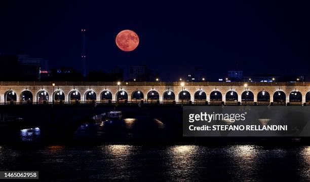 This photograph taken in Paris on July 3, 2023 shows the July's supermoon, known as the Buck Moon, with the 'Pont de Bercy' in the foreground.