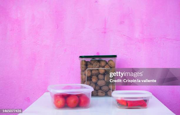 recyclable plastic food containers with tomatoes, peppers, nuts, pink background - plastic container stock pictures, royalty-free photos & images