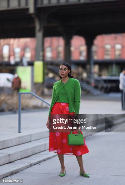 Olivia Joan seen wearing a daisy flower eye make up, gold necklace and earrings, Kate Spade knit green top and cardigan, Kate Spade red long skirt...
