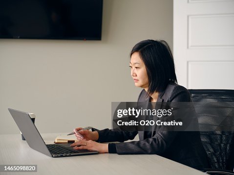Suing Computer Woman In An Office Usuing A Laptop Computer And Smartphone High-Res ...