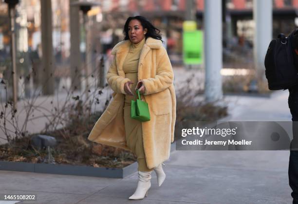 Guest seen wearing a yellow turtleneck long dress, a yellow fluffy long coat, Kate Spade green shiny leather handbag from, white shiny leather ankle...