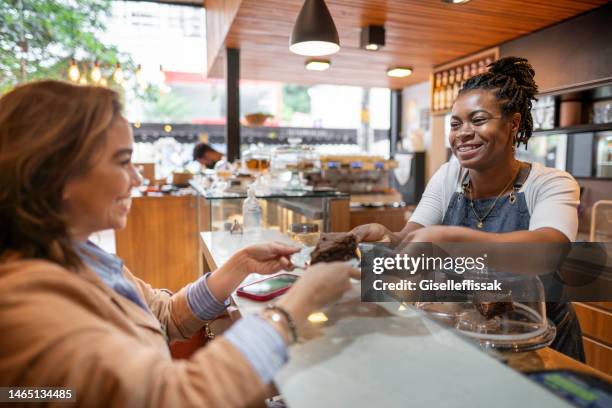 barista sorridente dando a um cliente um pedaço de bolo em um café - convenience - fotografias e filmes do acervo