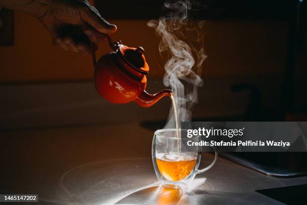 teapot pouring hot tea in transparent mug - green tea stock pictures, royalty-free photos & images