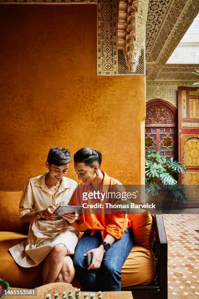 wide shot of smiling female couple looking at digital table in riad - premium access image only stock-fotos und bilder
