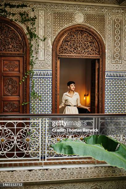 wide shot woman standing in bedroom window in raid while on vacation - trip photos et images de collection