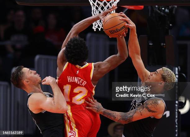Zach Collins and Jeremy Sochan of the San Antonio Spurs block a shot by De'Andre Hunter of the Atlanta Hawks during the first quarter at State Farm...