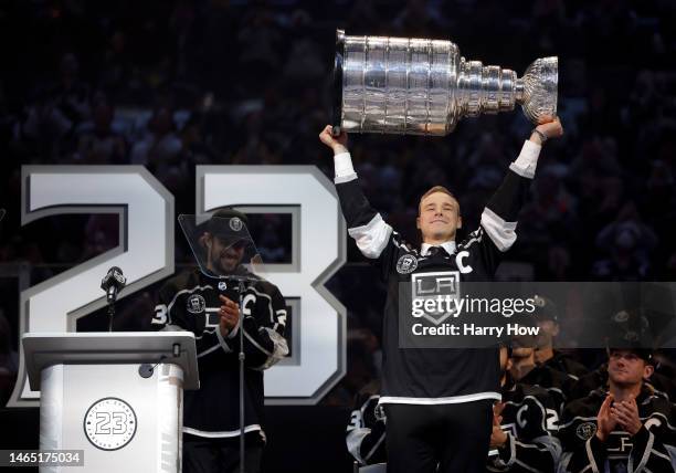 Dustin Brown of the Los Angeles Kings lifts the Stanley Cup during a ceremony as his jersey number is retired and a statue of his likeliness is...