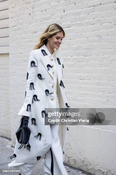 Actress Meghann Fahy wears embroidered white coat, button up jacket, pants, black bag outside Proenza Schouler during New York Fashion Week on...