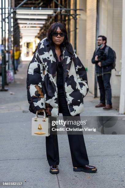 Guest wears Schiaparelli bag, jacket with cow print, black pants outside Proenza Schouler during New York Fashion Week on February 11, 2023 in New...