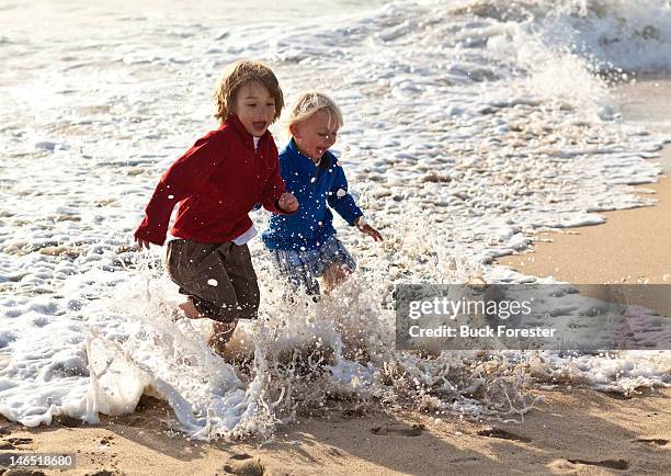 two boys running from waves - half moon bay california stock pictures, royalty-free photos & images