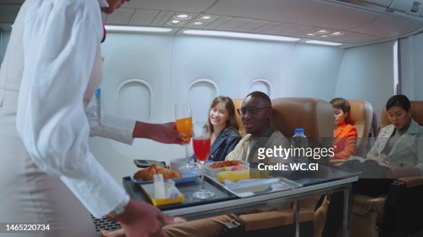 flight attendants serve food and drink to passengers during traveling on a plane - airline service stock pictures, royalty-free photos & images