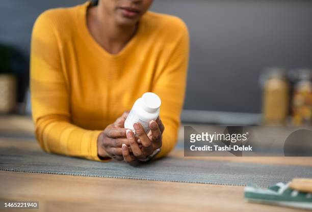 woman holding pill bottle - prescription medicine bottle stock pictures, royalty-free photos & images