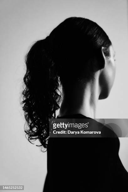 black and white portrait of a beautiful young woman on a gray background in a black dress. retro style. view from behind with copy space. - back of womens heads stockfoto's en -beelden