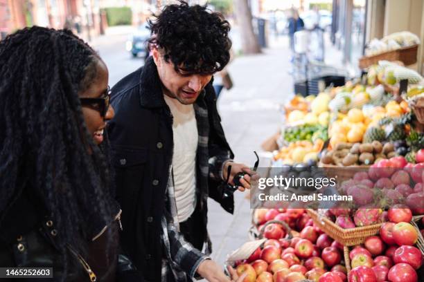 young couple selecting produce at the market - fruit stand stock pictures, royalty-free photos & images