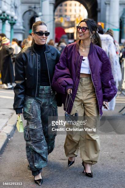 Hannah Lewis wears black bomber leather jacket, camouflage pants & Natalie Parvizian wears purple bomber jacket, beige pants outside PatBduring New...