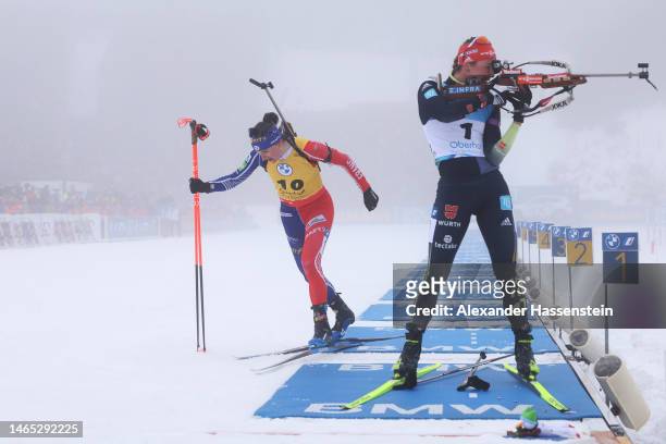 Julia Simon of France leaves the shooting section as Denise Herrmann-Wick of Germany shoots during the Women 10 km Pursuit at the IBU World...
