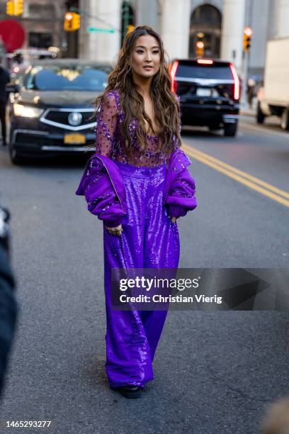 Actress Ashley Park wears purple sequined pants, see trough top, jacket outside PatBo during New York Fashion Week on February 11, 2023 in New York...