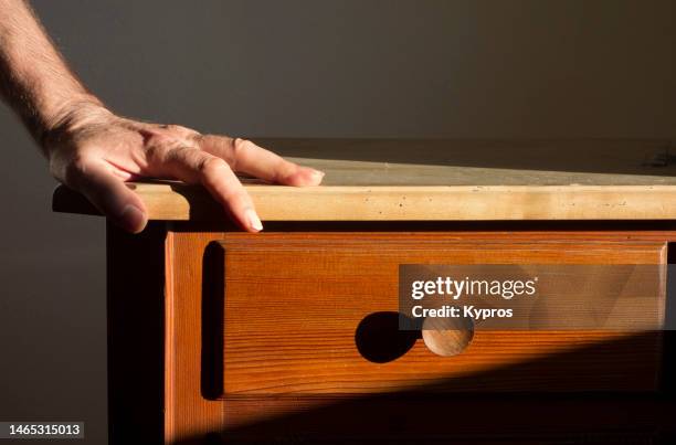 male hand resting on wood table - 引き出し ストックフォトと画像