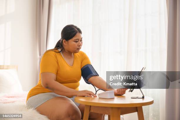 plus size woman examining her blood pressure and having video call with doctor. - diabetes care stock pictures, royalty-free photos & images