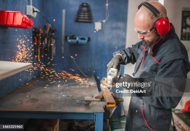 bearded metal worker using tools in a metal workshop - ear defenders stock pictures, royalty-free photos & images