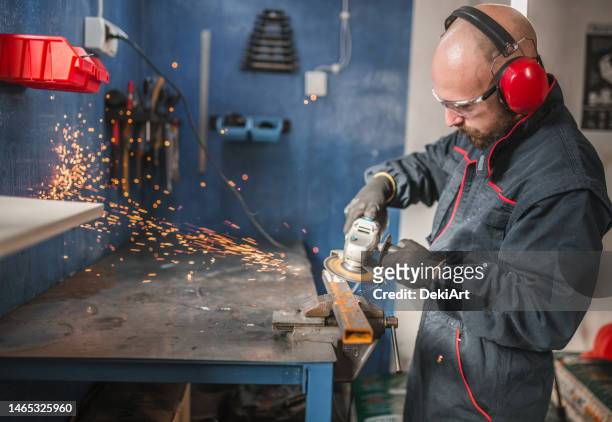 bearded metal worker using tools in a metal workshop - ear protection 個照片及圖片檔