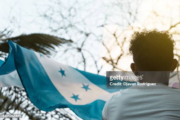 man from behind waving a honduran flag - honduras stock-fotos und bilder