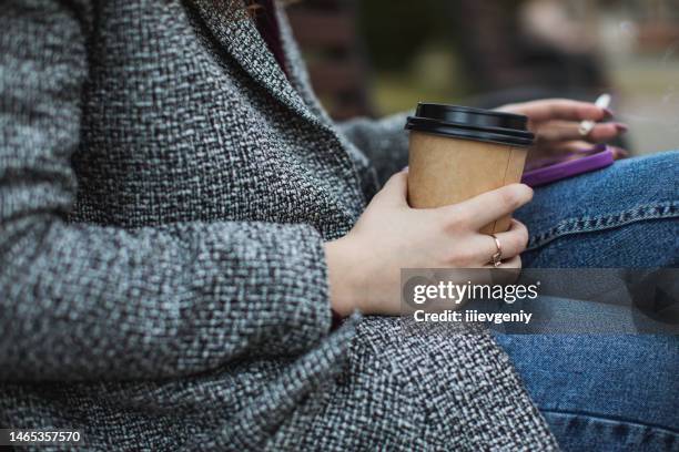 smoking. paper cup and mobile phone in hand - takeaway coffee stockfoto's en -beelden