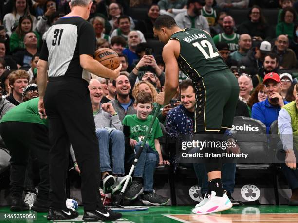 Grant Williams of the Boston Celtics helps clean up a spilled drink during the first quarter of a game against the Memphis Grizzlies at TD Garden on...