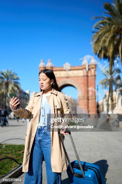 asian woman with suitcase in barcelona looking smartphone - asian tourist bildbanksfoton och bilder