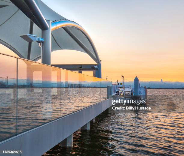 public ferry terminal on san francisco bay backlit by orange-colored sunset reflected in the salt water. - schwimmende plattform stock-fotos und bilder