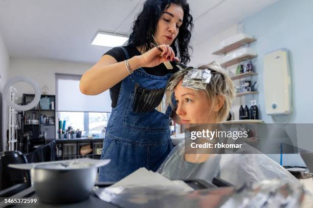 professional colorist applying hair dye - using hair dye foil in beauty salon - coloring stockfoto's en -beelden