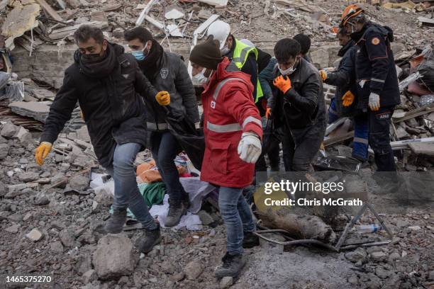 Volunteers and rescue teams carry a body from a destroyed building on February 12, 2023 in Adiyaman, Turkey. A 7.8-magnitude earthquake hit near...