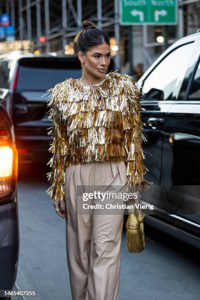 Vanessa Borelli wears golden fringed jacket, golden bag, beige pants outside Alice & Olivia during New York Fashion Week on February 11, 2023 in New...