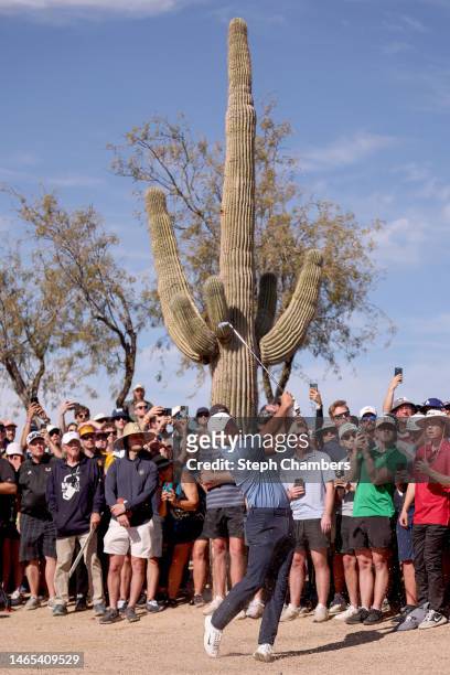 Scottie Scheffler of the United States plays an approach shot on the 14th hole as fans look on during the final round of the WM Phoenix Open at TPC...