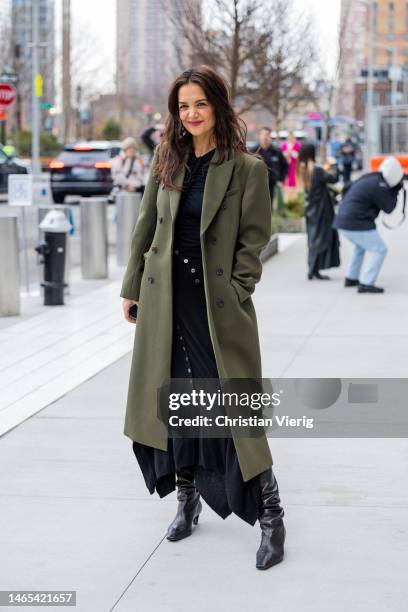 Katie Holmes wears green coat, black dress, boots, bag outside Ulla Johnson during New York Fashion Week on February 12, 2023 in New York City.