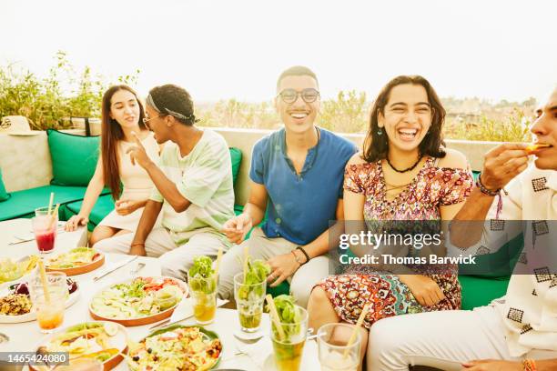 medium shot of friends laughing during meal at rooftop restaurant - rooftop dining foto e immagini stock