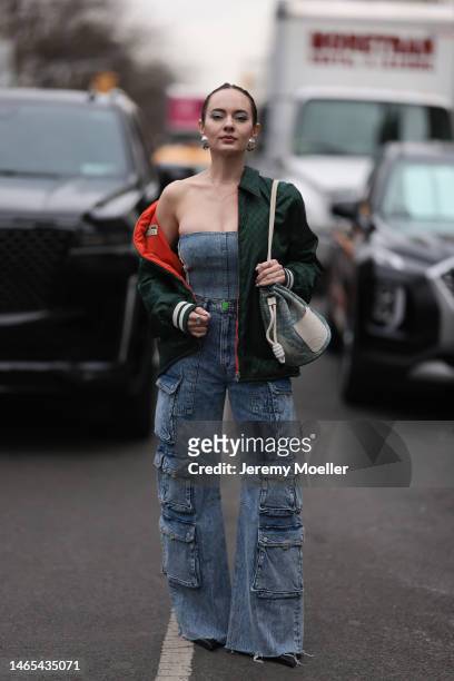 Katya Bychkova is seen wearing silver hairclips, Hudson Jeans wide-leg cargo denim pants, a Loewe bucket denim logo bag, Gucci logo dark green nylon...