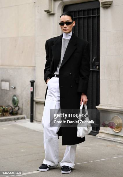 Model Lina Zhang is seen wearing a black coat, gray Prada sweater, white pants and black sunglasses outside the Jason Wu show during New York Fashion...