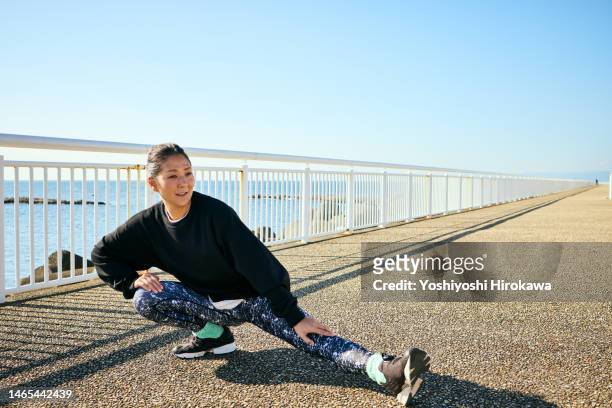 mother stretches by the sea - fitness or vitality or sport and women fotografías e imágenes de stock